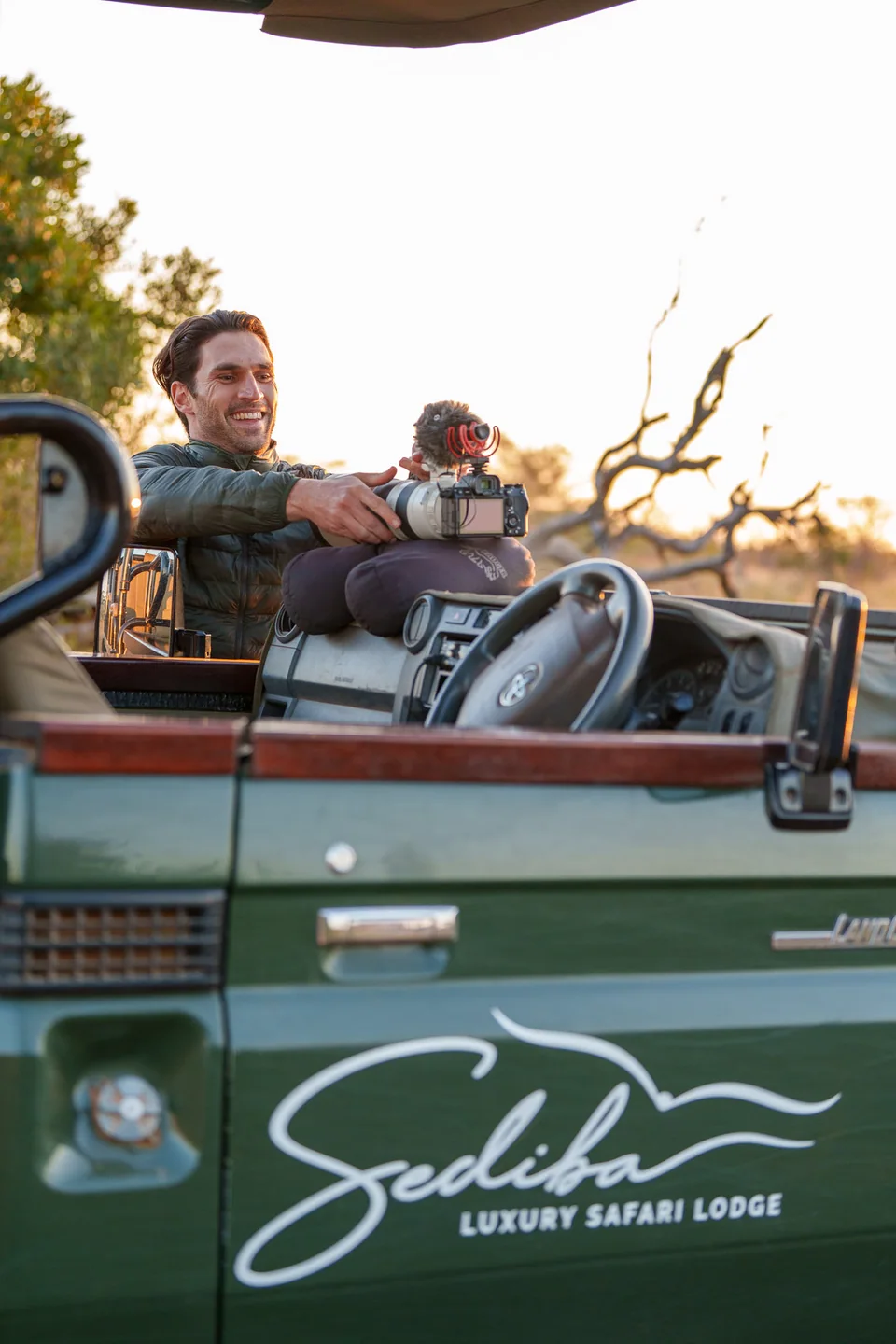 A photographer with a camera and microphone on a Sediba safari vehicle
