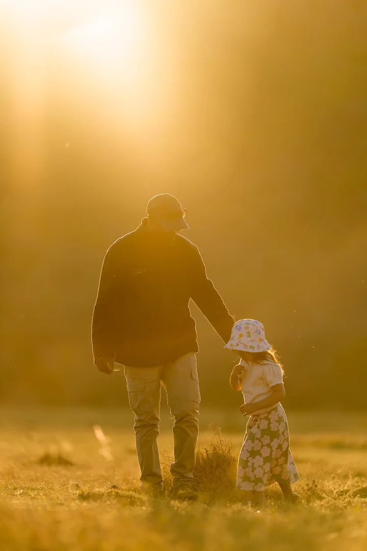 An adult and a child enjoying the golden evening light in the bush.