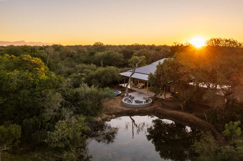 A Nomads Den villa beside its private dam at sunset